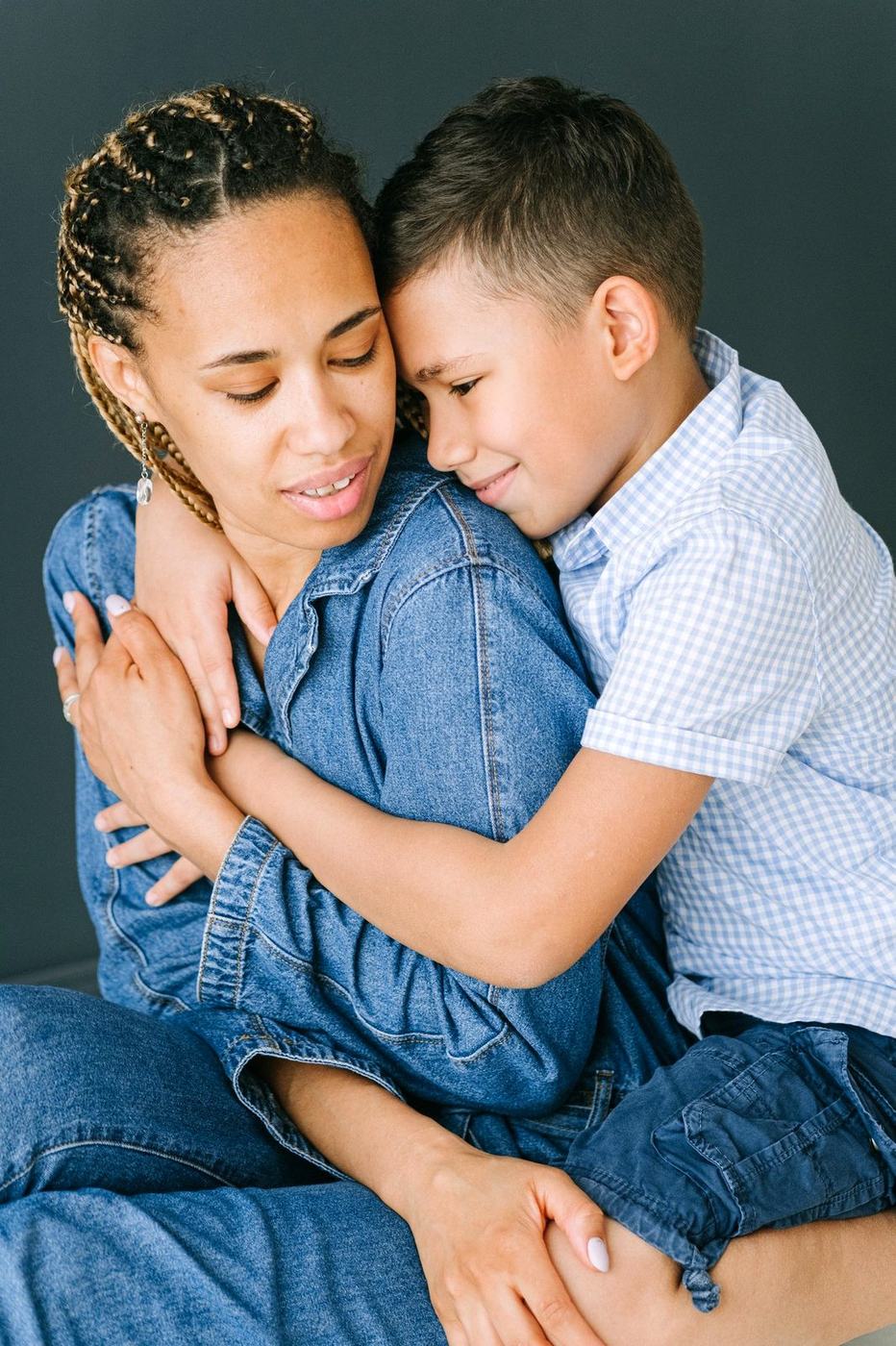 Mãe abraçando o filho com os olhos fechados, em um gesto de acolhimento