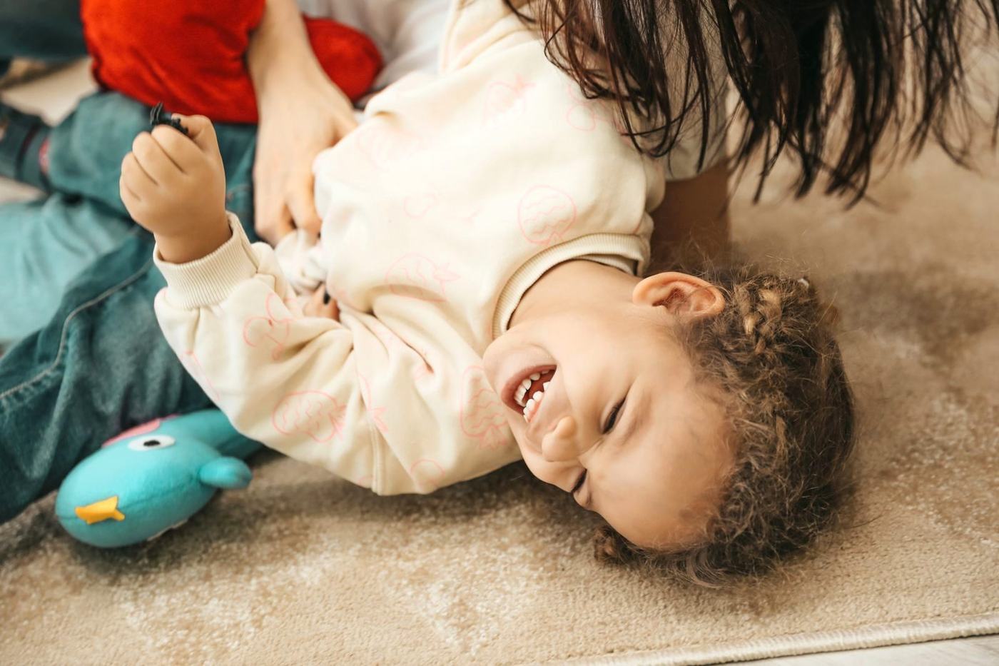 Mãe e filho brincando juntos no tapete de casa, rindo