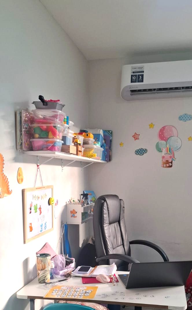 Sala de terapia com prateleira de materiais e quadro de rotina visual